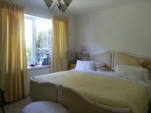 a bedroom with a bed with yellow curtains and a window at Folly Studio Bed and Breakfast in Bungay