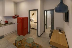 a kitchen with a red refrigerator and a room with a bed at TRIA NOMINA Apartamentos Turísticos in Mérida