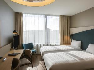 a hotel room with two beds and a desk at Aparthotel Adagio London Stratford in London +63 photos