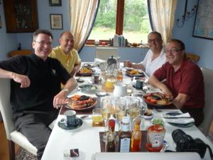 um grupo de homens sentados à volta de uma mesa a comer comida em Amalfi Bed and Breakfast em Dornoch