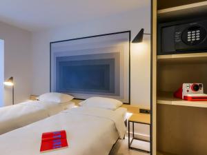 two beds in a hotel room with a tv at ibis Timisoara City Center in Timişoara