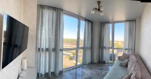 a living room with a couch and large windows at Апартаменти Промінь ЖК яровиця Луцьк in Luts'k