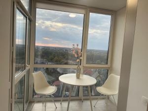 a table and chairs in a room with large windows at Апартаменти Промінь ЖК яровиця Луцьк in Luts'k