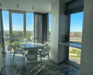 a dining room with a table and chairs and large windows at Апартаменти Промінь ЖК яровиця Луцьк in Luts'k