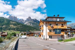 a building on the side of a road with mountains at Appartamento Nuovo A San Giovanni in Pozza di Fassa