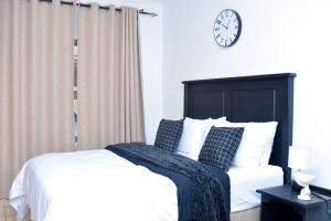 Un dormitorio con una cama y un reloj en la pared. en House For Four Adults, en Witbank