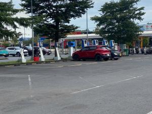 a red car parked in a parking lot at a gas station at Nha Nghi Phu Gia in Phú Mỹ