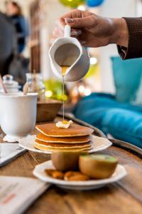 a person pouring syrup onto a stack of pancakes at Demeures de Campagne Parc du Coudray - Barbizon in Le Coudray-Montceaux +46 photos