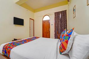 a bedroom with a bed and a window and a television at FabHotel Martines Residency in Pondicherry