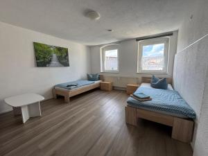 ゲーラにあるBüchner 50のベッド2台、テーブル、窓2つが備わる客室です。
