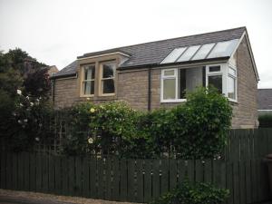 a house with a fence in front of it at StoneLaw Cottage in Longframlington