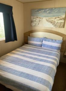 a bedroom with a bed with blue and white stripes at Caravan Meg 3 bed robin holiday in Rhyl
