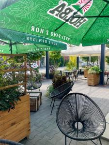 a patio with tables and chairs under a green umbrella at ART Pensjonat in Krotoszyn