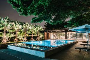 a swimming pool with an umbrella and a building at The Platinum Suites Bangkok by Dancenter in Sathani Khlong Tan