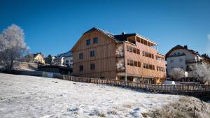 a large wooden building in the snow next to a field at Haus Weigt - Appartement das Grüne in Mariapfarr