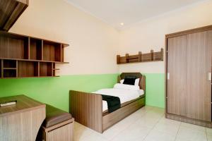 Un dormitorio con una cama y una pared verde. en OYO 94632 Griya Cewang Syariah, en Bekasi