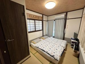 a small bedroom with a bed and a window at Ryokoheya Awajikan in Osaka