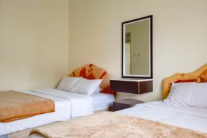 a hotel room with two beds and a mirror at Homestay Nusa Indah 2 Syariah at Dieng 0 KM RedPartner in Dieng