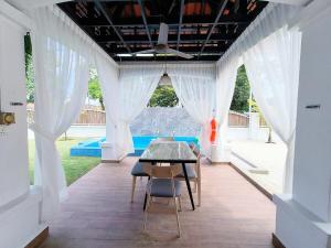 a dining room with white curtains and a table and chairs at Luxpro Private Pool Bungalow Seremban in Seremban