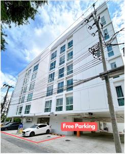 ein weißes Auto, das vor einem weißen Gebäude parkt in der Unterkunft Wonderful Stay BTS Ratchayothin in Bangkok