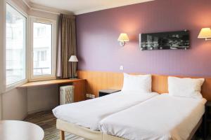 a hotel room with two beds and a window at Bright studio apartment with parking and balcony in Issy-les-Moulineaux