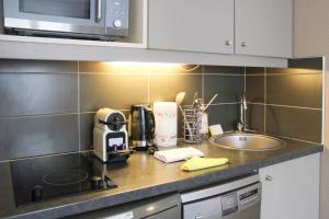 a kitchen counter with a coffee maker and a sink at Bright studio apartment with parking and balcony in Issy-les-Moulineaux +12 photos