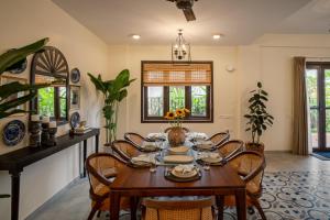 una sala da pranzo con tavolo e sedie in legno di Villa Orla Luxurious 4bhk with Pvt Pool, Lift, Spa ad Arpora