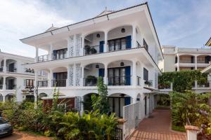un edificio bianco con balconi e alberi di Villa Orla Luxurious 4bhk with Pvt Pool, Lift, Spa ad Arpora