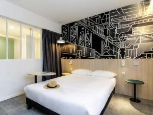 - une chambre avec un lit blanc et un mur noir et blanc dans l'établissement ibis Styles Limoges Centre, à Limoges