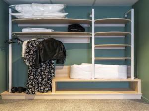 Un armario con estantes de madera y toallas blancas. en ibis Styles Limoges Centre, en Limoges