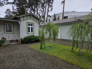 a white house with trees in the yard at Baltic beach villa 2 in Jūrmala