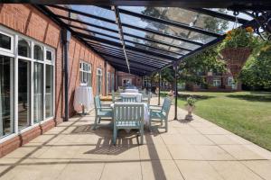 a patio with a table and chairs under a pergola at DoubleTree by Hilton St. Anne's Manor in Bracknell