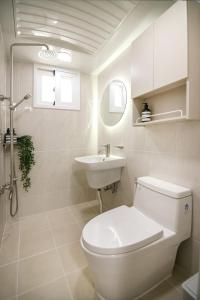 a white bathroom with a toilet and a sink at wonjong stay 101 김포공항 in Pakkosi