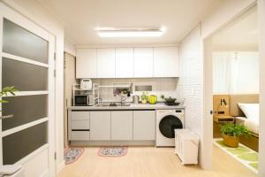 a small kitchen with white cabinets and a sink at wonjong stay 101 김포공항 in Pakkosi