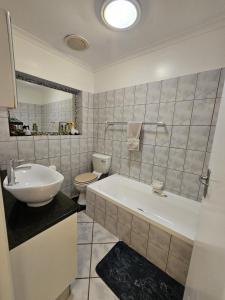 a bathroom with a tub and a toilet and a sink at River Apartment in Gated Complex in Keurboomstrand +9 photos
