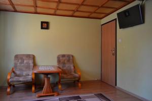 a room with two chairs and a table and a television at Kwatera Pod Lasem in Istebna