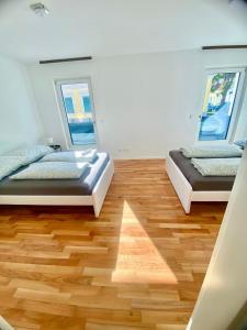 two beds in a room with wood floors and two windows at Modern 2 Bedroom Apartment in Vienna
