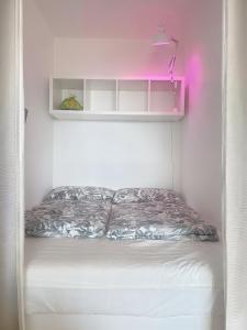 a bed in a white room with a pink light at Kerzen Boutique in Bad Salzuflen