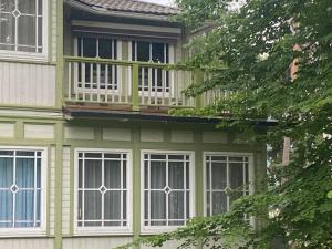 a green house with a balcony and windows at Baltic beach villa 2 in Jūrmala