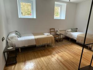 a room with two beds and a table and two windows at Apartamentos Pirineo in Isaba