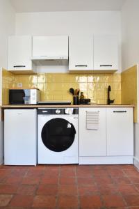 a kitchen with a white dishwasher and white cabinets at Le Petit Cèpe - Hyper Centre Bergerac in Bergerac