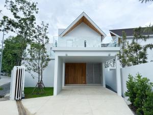 une maison blanche avec une porte en bois et une clôture dans l'établissement Bangtao Luxury 4 bedroom villa Lux Pride, à Ban Pak Lak