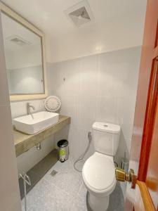 a bathroom with a white toilet and a sink at The Blue Doors- Siargao in General Luna