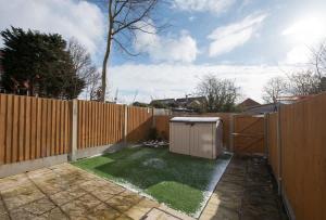ein Hinterhof mit einem Holzzaun und einem kleinen Gerät in der Unterkunft Parking Space, Doors onto Garden-Pet Friendly in Romford