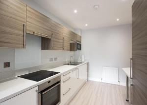 eine Küche mit weißen Arbeitsplatten und Holzschränken in der Unterkunft Parking Space, Doors onto Garden-Pet Friendly in Romford + 47 Fotos