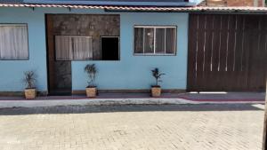 a blue house with two doors and two potted plants at Espaço familiar 3 in Vila Velha