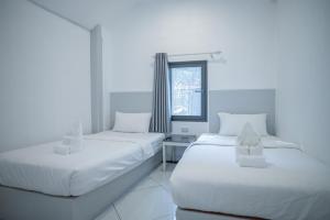 two beds in a white room with a window at DownTown Hotel in Luang Prabang +23 photos