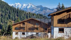 a large wooden building with mountains in the background at ASAI707-C03 Appartement 3 pièces - Les Saisies - 7 personnes in Les Saisies +9 photos