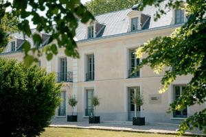 a building with potted plants in front of it at Hotel Mercure Parc du Coudray - Barbizon in Le Coudray-Montceaux