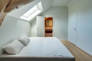 ein Schlafzimmer mit einem weißen Bett und einem Dachfenster in der Unterkunft Ferme de Pétrieux - Gîte "Le Tilleul" avec piscine et wellness in Tournai